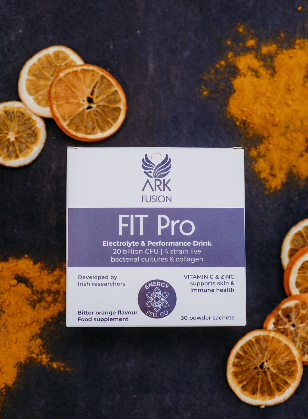 A box of FIT Pro supplement powder with slices of orange and a pot of powder visible in the background.